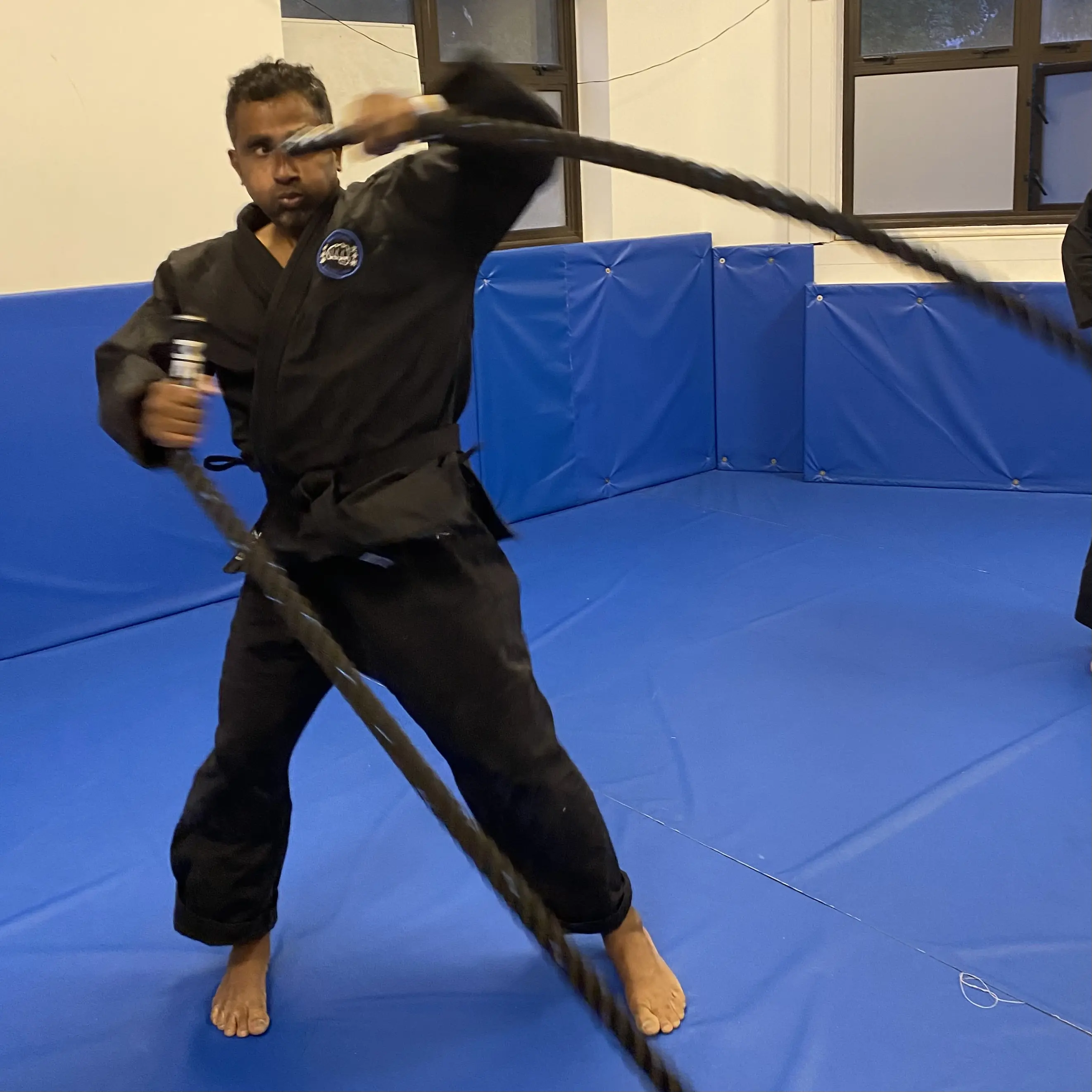 John Moses of Shuhari Self Defence Bracknell warming up before martial arts class doing uppercuts and hooks with battle rope